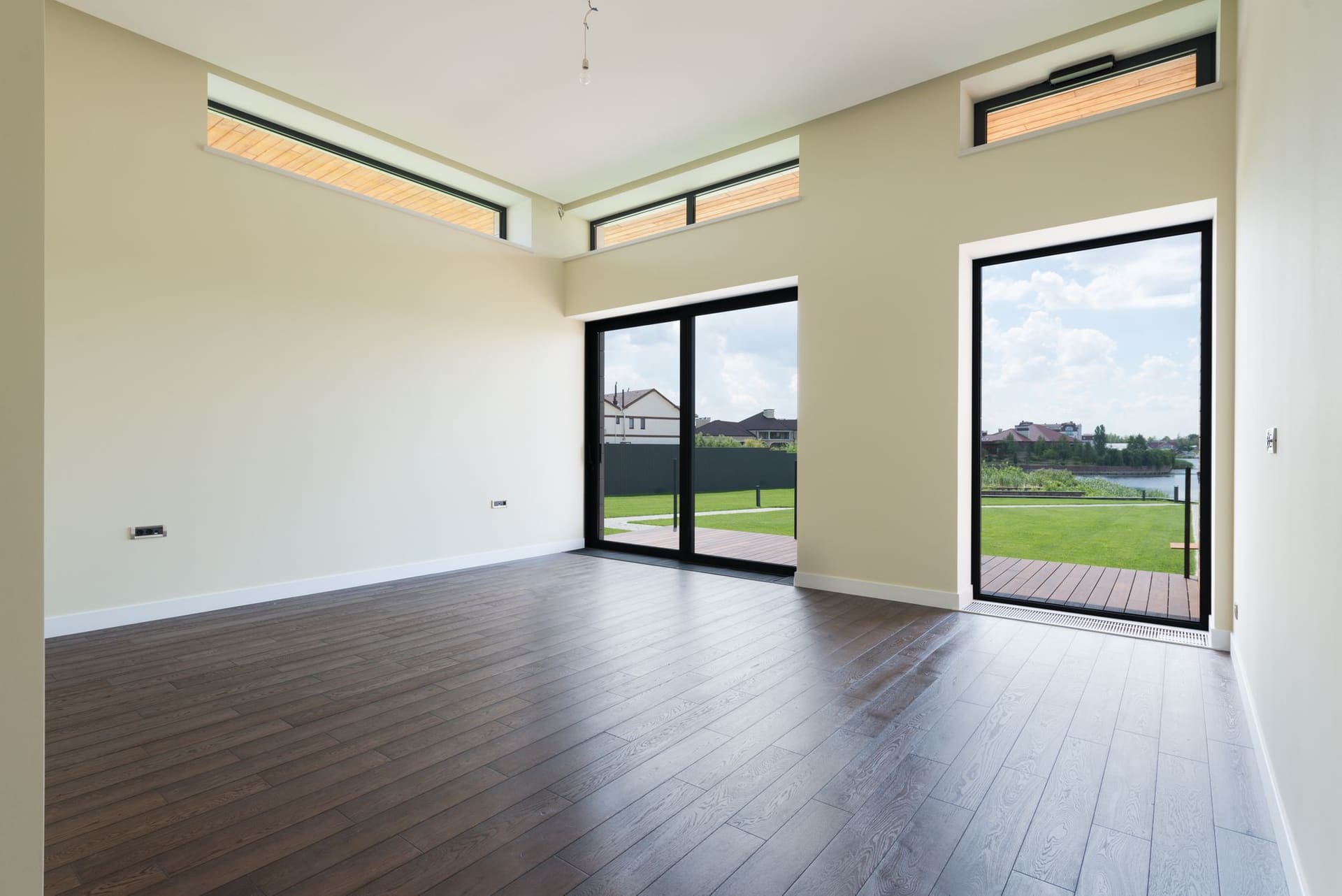 An empty, bright living room with floor-to-ceiling windows